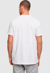 Hvid bomulds t-shirt med korte ærmer, en rund halsudskæring og en ensfarvet ryg. Stofret er glat med en let tætsiddende silhuet.