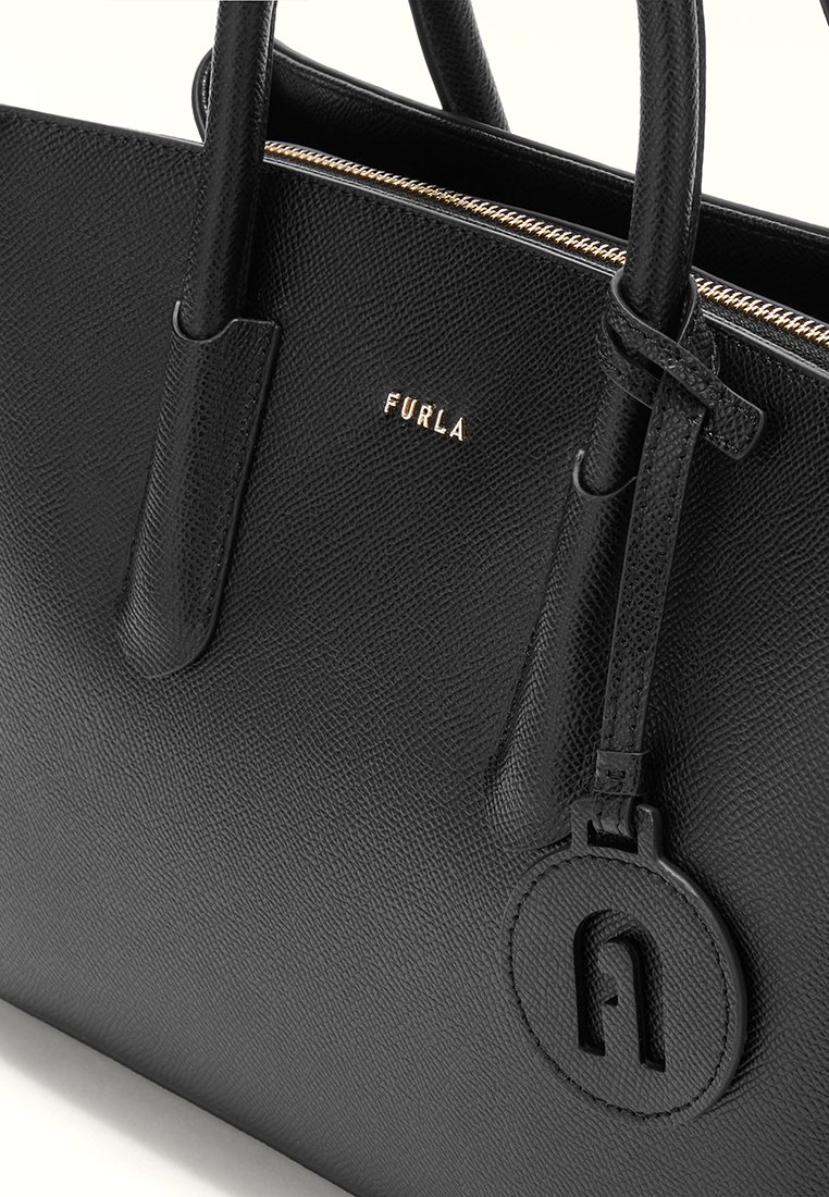 Bolso de mano de cuero negro con superficie texturizada, doble asa y herrajes dorados. Presenta una etiqueta circular con detalle del logo. Cierre de cremallera.