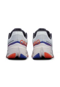 Weiße Laufschuhe mit einer strukturierten Oberseite, kontrastierender dunkler Ferse, auffälligem "ON RUNNING"-Schriftzug in Orange und einer mehrfarbigen Außensohle mit roten und blauen Akzenten.