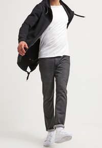 Černá mikina s žebrovanou strukturou, bílý tričko, šedé kalhoty a bílé tenisky. Neformální outfit s volným střih a vrstveným designem.