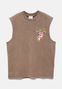 Chemise marron sans manches avec un logo des Rolling Stones comportant une langue rouge et un fer à cheval sur le devant en haut à gauche.