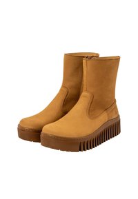 Tan leren enkelboots met een glanzende afwerking, elastische zijkanten en een geribbelde rubberen zool voor grip. Beschikt over een minimalistisch ontwerp.