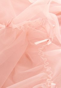 Svetloružová tylová tkanina s volánikovými okrajmi a jemnými saténovými mašličkami. Mäkká textúra s vrstvenou priehľadnosťou a plynulým závesom.