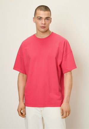 Roze t-shirt met korte mouwen van zacht katoen, relaxte boxy fit, ronde halslijn, zichtbare stiksel-details, model draagt witte broek.
