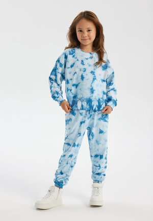 Blue tie-dye sweatshirt and matching joggers made from soft fabric, featuring elastic cuffs and a relaxed fit, paired with white high-top sneakers.