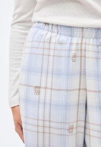 Φωτεινό γαλάζιο καρό πυτζάμα με μπεζ λεπτομέρειες· διαθέτει μικρές εικόνες αρκουδάκι και ελαστική μέση για άνεση.