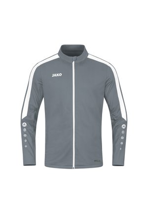 Veste de sport grise avec des rayures blanches sur les côtés, col montant, fermeture éclair sur toute la longueur et accents de logo rond sur les manches. Texture légère et lisse.