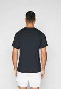 Svart trenings-T-skjorte med korte ermer, rund hals og tettsittende design. Glatt tekstur, lett stoff, sømløse skulderdetaljer.