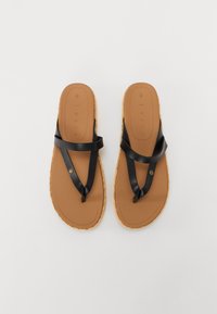 Mustat flip-flopit, joissa on teksturoitu ruskea kumipohja. Minimalistinen muotoilu, jossa on ohuet hihnat ja pieni metallinen logoyksitys.