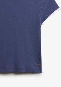 Camiseta de manga corta azul marino de algodón suave, con corte recto y logo bordado en dorado en el dobladillo. Textura lisa sin estampados.