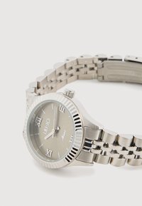 Orologio da polso in metallo con cinturino argentato, quadrante rotondo, dial grigio, numeri romani e lunetta texturizzata. Presenta una corona sul lato.