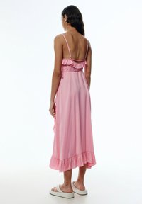 Rosa ärmelloses Kleid aus leichtem Stoff mit Rüschen am Ausschnitt und Saum, mit einer fließenden Silhouette.