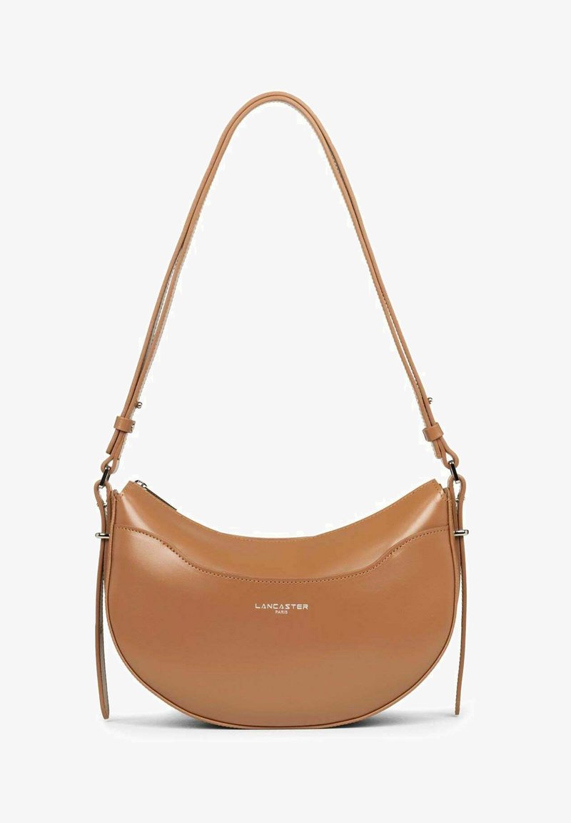 Borsa a mano in pelle color tan con forma curvata e una lunga tracolla. Presenta una chiusura con zip e un logo del marchio in rilievo sul davanti. Texture liscia.