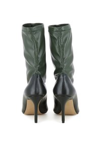 Bottes de cheville en cuir vert avec une texture douce, bout pointu et talons de 10 cm. Présente un design à rabat et un talon noir contrastant.