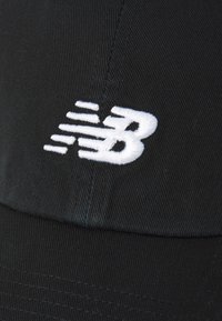 Cappello in tessuto nero con logo New Balance ricamato in bianco, caratterizzato da un design dinamico che mette in evidenza texture e dettagli di cucitura sottili.