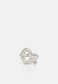 Silver metal ring shaped like a twisted heart, featuring smooth lines and embedded clear gemstones on either side.