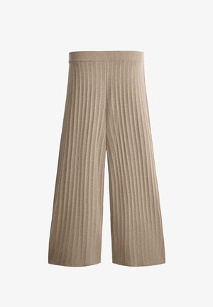 Bež široke pletene hlače z navpičnim rebrastim vzorcem in elastičnim pasom, položene ravno na belem ozadju.