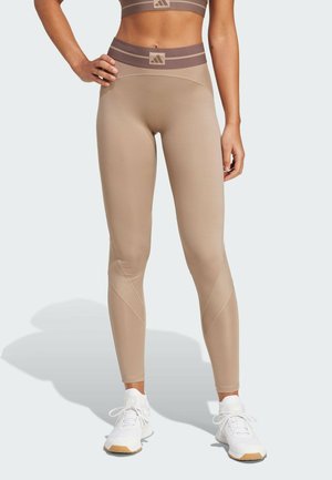 Beige hoge taille legging met gemêleerde accenten en een bruine gestreepte tailleband. Het materiaal lijkt rekbaar en soepel, geschikt voor sportkleding.
