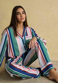 Striped pajama set with green, pink, blue, and red hues; long sleeves; button-up shirt with a chest pocket; soft, silky fabric.