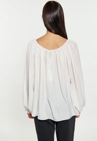 Weiße, fließende Bluse mit weitem Ausschnitt und langen, gerafften Ärmeln. Glattes, leichtes Gewebe mit sanftem Fall. Überlappendes Rücken-Design.