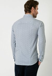 Witte shirt met een blauw geometrisch patroon, lange mouwen, knoopmanchetten en een puntige kraag. Glad materiaal met een slim-fit ontwerp.