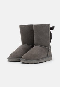 Bottines en daim gris avec un bout arrondi, dotées d'une doublure douce et d'un nœud décoratif à l'arrière. Semelle extérieure en caoutchouc plate pour une meilleure adhérence.