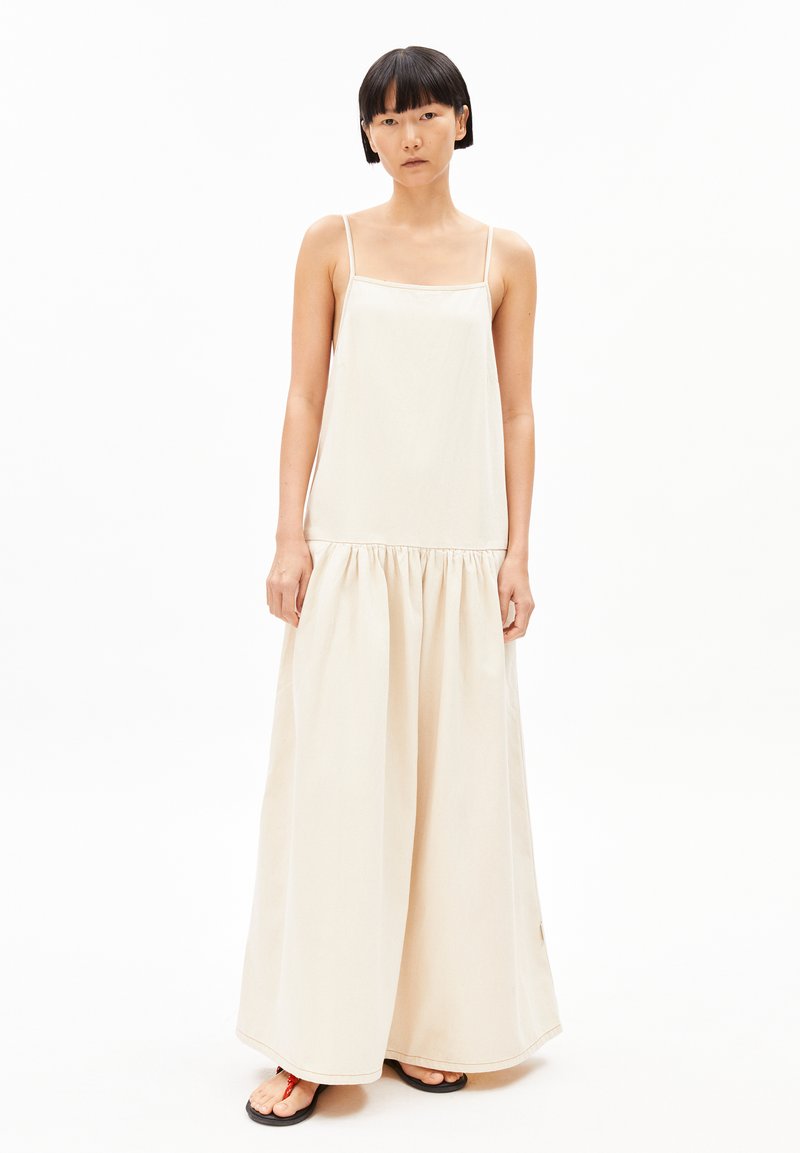 Beiges Maxikleid mit dünnen Trägern, lockerer Passform, gerafftem Taillenbereich und fließendem Rock. Geschmeidiger Baumwollstoff und Schlitzsaumdetail.