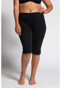 Leggings neri fino al ginocchio realizzati in un tessuto misto cotone, con una vita elastica e una texture liscia senza fantasie o accessori.