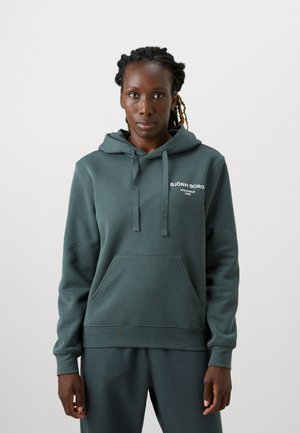 Sweat à capuche vert avec un cordon de serrage, poche kangourou et détails de logo blancs. Fabriqué en tissu doux avec une coupe décontractée et des poignets côtelés.