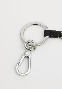 Metal keychain with a silver ring and a black leather accent, featuring a spring-loaded clip for easy attachment and a logo engraving.