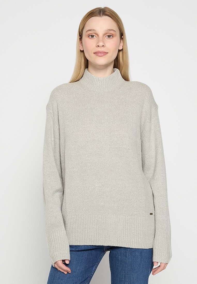 Maglione a collo alto grigio chiaro realizzato in morbido knit con polsini e orlo a coste. Presenta una vestibilità morbida e una texture sottile per un comfort aggiuntivo.