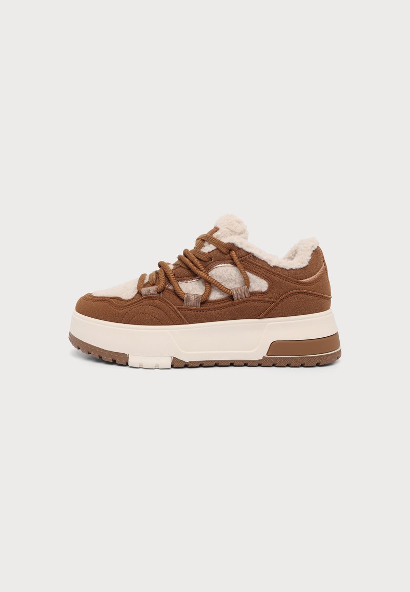 Baskets marron et beige avec une semelle blanche épaisse, un design à lacets et une doublure en polaire douce visible sur la tige et la languette.