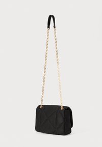Black quilted handbag made of suede material. Features a gold chain strap and a folded design with prominent stitching details.