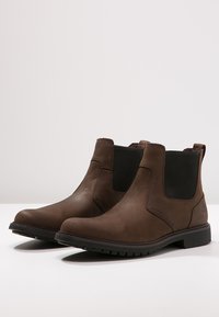 Brown leather Chelsea boots with elastic side panels, rounded toe, rubber sole, and minimal stitching detail. Suitable for casual wear.