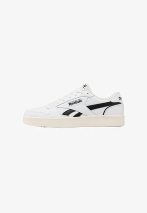 Sneaker bassa bianca Reebok con strisce nere laterali con logo e suola beige, vista dal lato esterno.