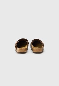 Sandales ouvertes marron avec une semelle en liège, deux boucles et un dessus en cuir texturé. Design plat avec un soutien de la voûte plantaire minimal.