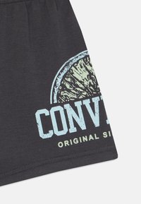 Dunkelgraues Baumwoll-T-Shirt mit einem großen Grafikmotiv einer Limettenscheibe und dem Text "CONVERSE ORIGINAL SIGN" in Blau.