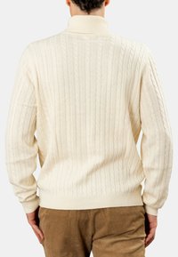 Maglione crema a vitt à treccia con colletto alto e polsini a coste. Presenta una texture a coste verticali sulla schiena e un orlo aderente.