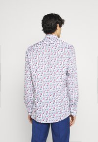 Chemise blanche à manches longues avec un motif floral multicolore, col boutonné et coupe classique, avec des boutons aux poignets.