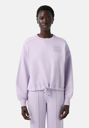 Sweatshirt lavande clair avec un col rond, des poignets côtelés et un ourlet avec cordon de serrage. Présente un logo texturé sur le haut à gauche de la poitrine.