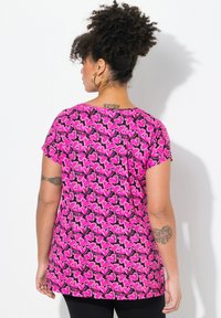 Camisa rosa de manga corta con un patrón repetido de corazones y siluetas. Fabricada en un tejido suave, tiene un ajuste relajado y un escote redondeado.