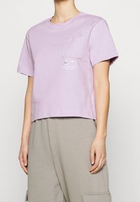 Ljuslila croppad t-shirt i bomull med en framficka och en liten Nike-logga tryckt på bröstet. Korta ärmar.