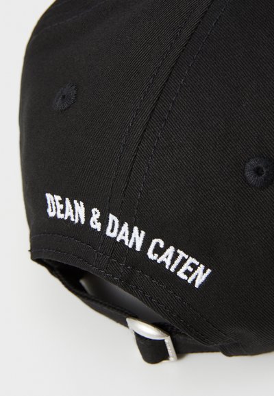 Black baseball cap made of fabric featuring white embroidered text "DEAN & DAN CATEN" on the back, with a metal buckle for adjustment.