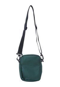 Zelená látková crossbody taška štvorcového tvaru, s nastaviteľným čiernym popruhom, zipsom na uzatváranie a textúrovaným povrchom.