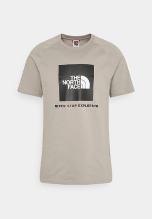 Camiseta de algodón de color beige claro con mangas cortas, que presenta un gráfico cuadrado negro con "THE NORTH FACE" y "NEVER STOP EXPLORING" en blanco.