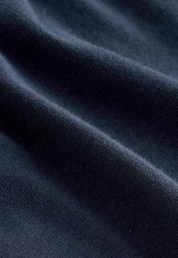 Tela de un azul marino oscuro con una textura suave y lisa, y un sutil patrón de tejido, que muestra pliegues suaves y variadas reflexiones de luz.