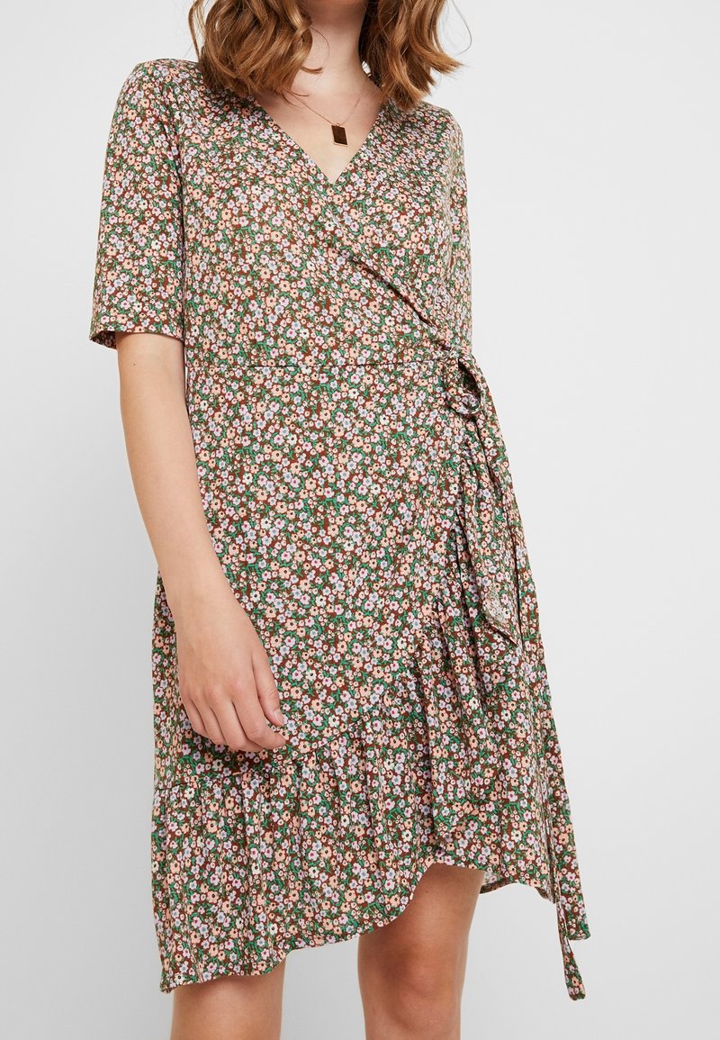 Kwiatowa sukienka w odcieniu brązu, z krótkimi rękawami, wiązaniem w talii i falbaną u dołu, w różowe i białe wzory kwiatowe.