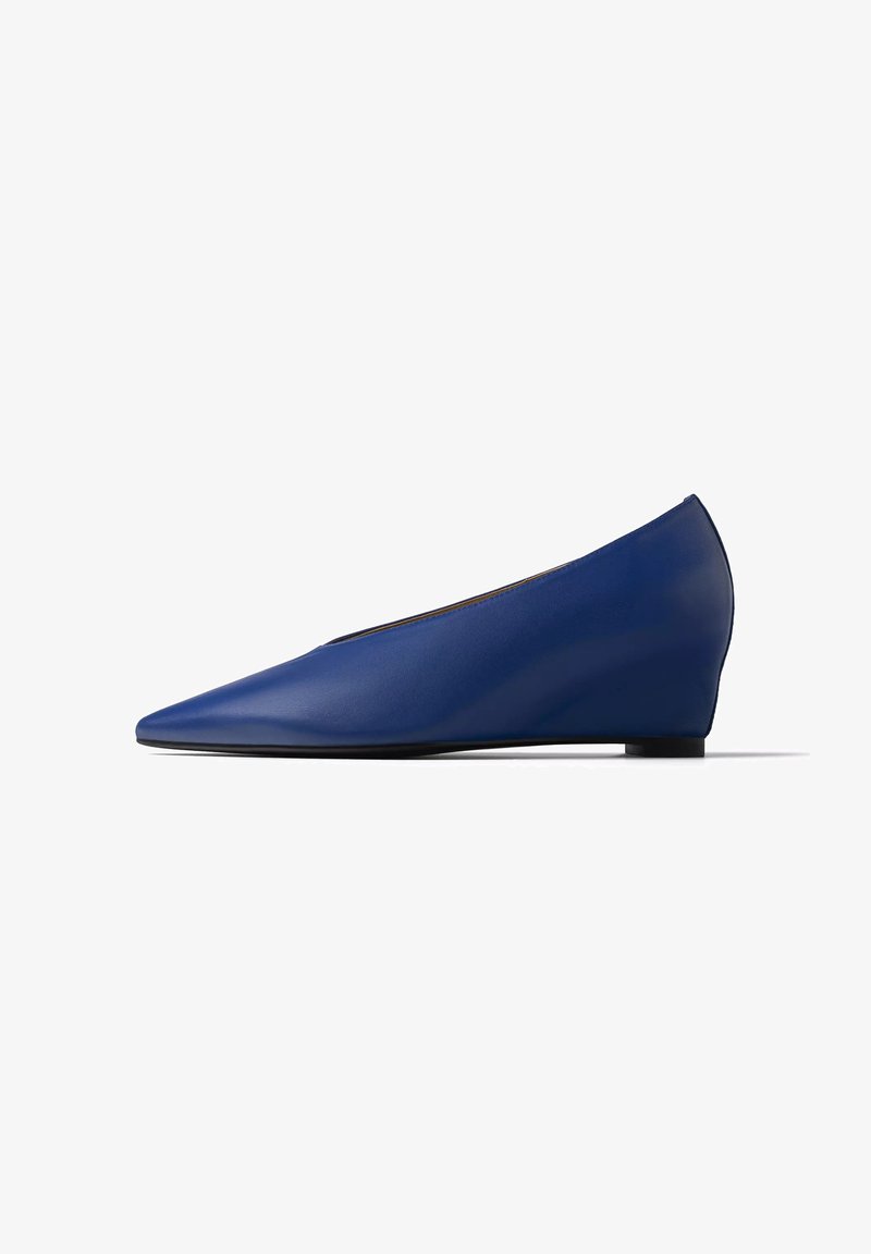 Chaussure compensée en cuir bleu pour femme avec bout pointu et talon bas, vue de profil sur fond blanc.