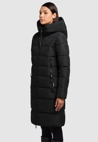 Zwarte donsjas met een hoge kraag, horizontale gewatteerde structuur, twee zijritsen en een voorrits. Lange mouwen met manchetdetails.