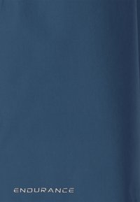 Blåt stofoverflade med ordet "ENDURANCE" trykt i hvide små bogstaver nær den nederste kant.